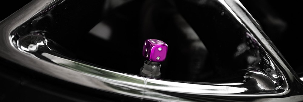 This image shows a purple dice dust cap on a chrome rim